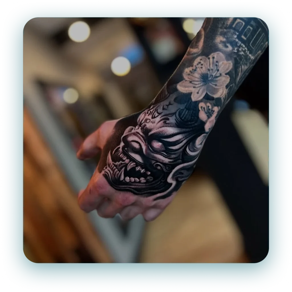 black-and-grey-realism-ancient-oni-mask-skull-hand-tattoo